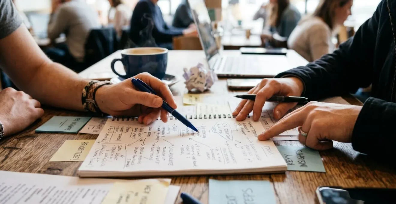 Deux mains posées sur une table avec des notes manuscrites, ambiance de discussion constructive et collaborative