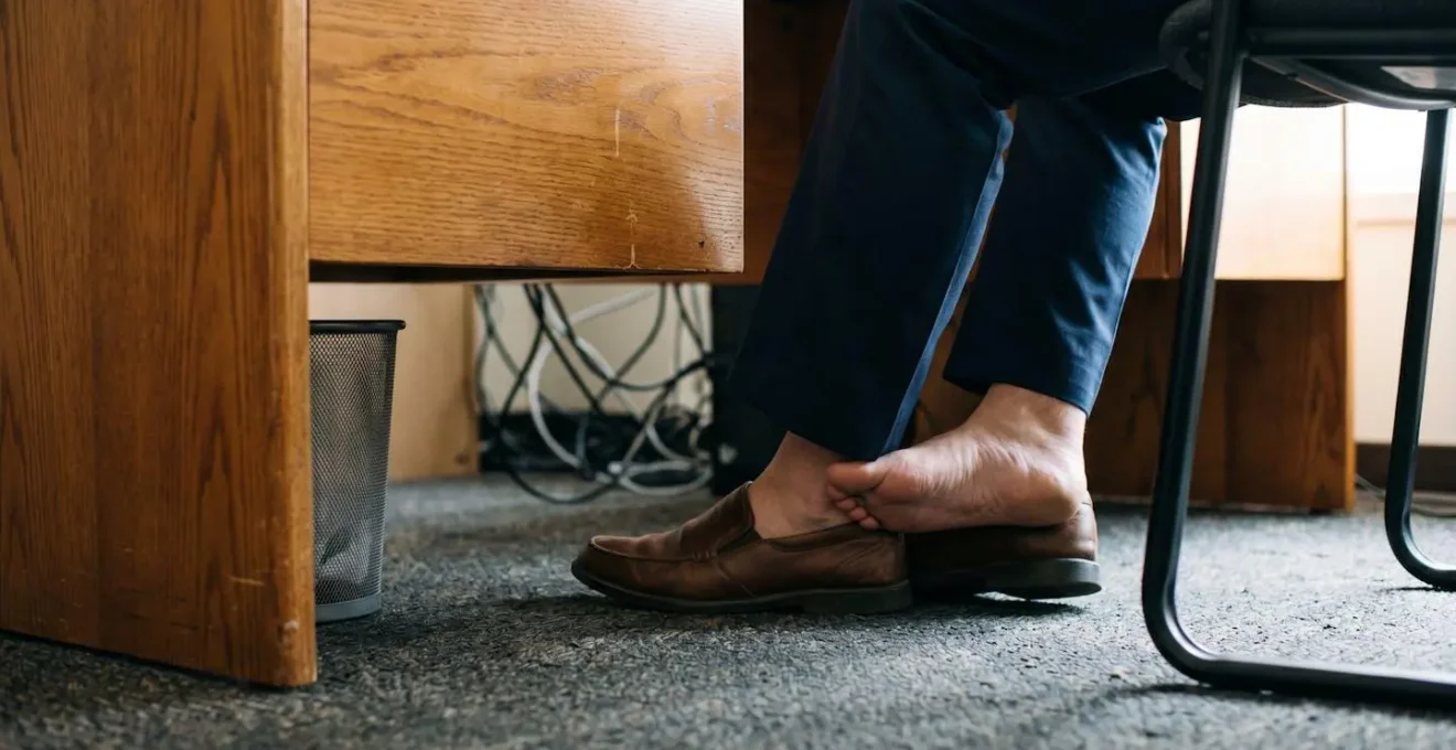Gros plan sur des jambes sous un bureau illustrant une technique de relaxation discrète
